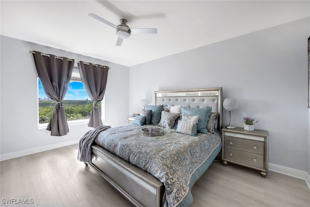 bedroom with light wood-style floors, ceiling fan, and baseboards