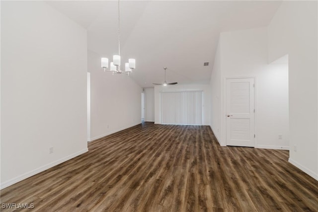 spare room with baseboards, dark wood-type flooring, a high ceiling, and a notable chandelier