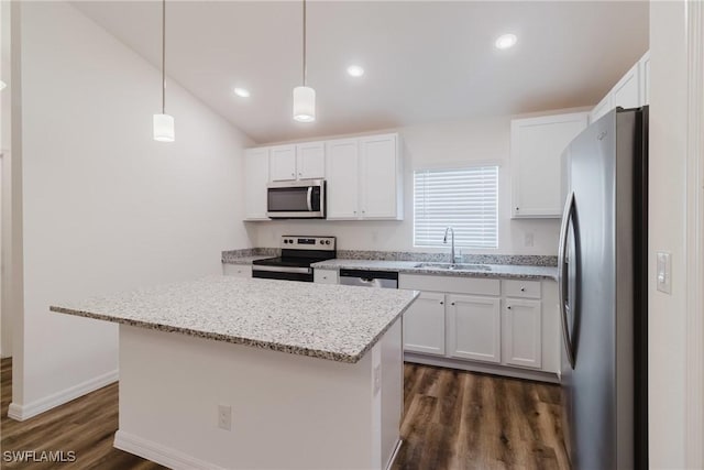 kitchen with stainless steel appliances, a sink, a kitchen island, white cabinets, and hanging light fixtures