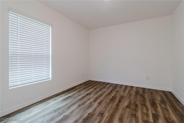 spare room with baseboards and dark wood-style flooring