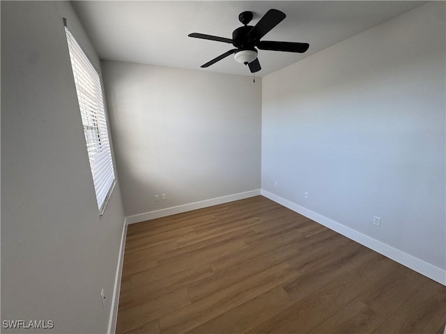 unfurnished room featuring baseboards, dark wood finished floors, and a ceiling fan