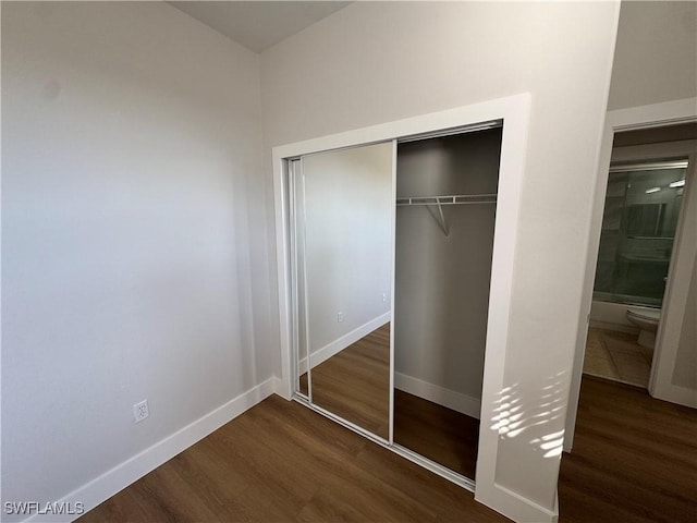 unfurnished bedroom featuring baseboards, dark wood finished floors, and a closet