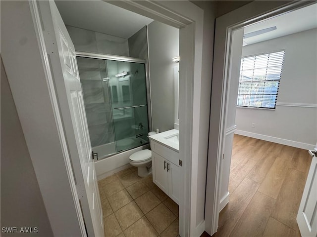 full bathroom featuring toilet, shower / bath combination with glass door, wood finished floors, vanity, and baseboards