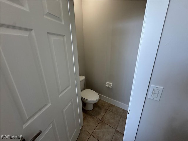 bathroom with toilet, baseboards, and tile patterned floors