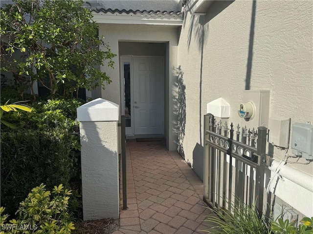 property entrance with a tiled roof and stucco siding