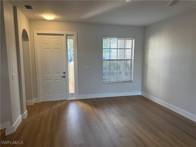 entryway featuring dark wood-type flooring, arched walkways, visible vents, and baseboards