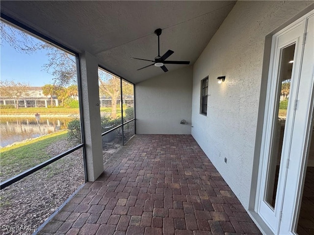 unfurnished sunroom with vaulted ceiling, a water view, and ceiling fan