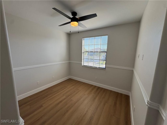 spare room with wood finished floors, a ceiling fan, and baseboards