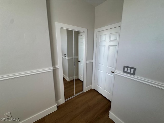 corridor with dark wood-style flooring and baseboards