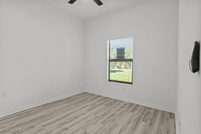 spare room with a ceiling fan, light wood-style flooring, and baseboards