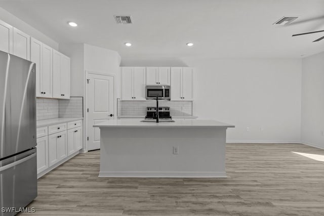 kitchen with light wood finished floors, visible vents, appliances with stainless steel finishes, and white cabinets