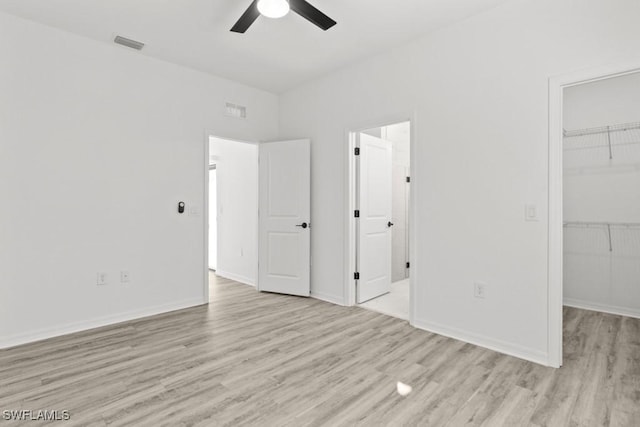 unfurnished bedroom featuring light wood-style floors, visible vents, and a walk in closet