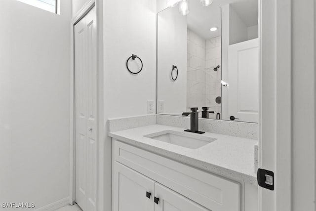 bathroom featuring a closet, a tile shower, vanity, and baseboards