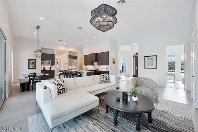 living room with a high ceiling, recessed lighting, visible vents, and a notable chandelier