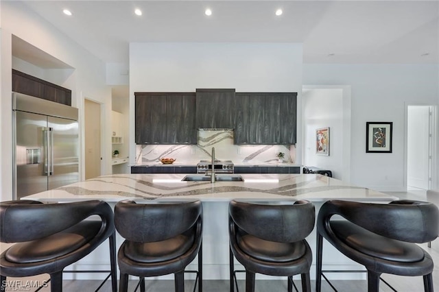 kitchen featuring built in refrigerator, modern cabinets, a sink, and a kitchen breakfast bar