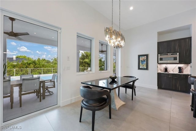 dining space featuring baseboards and ceiling fan with notable chandelier