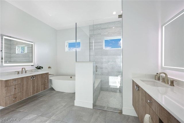 full bathroom with a freestanding tub, a shower stall, two vanities, and a sink