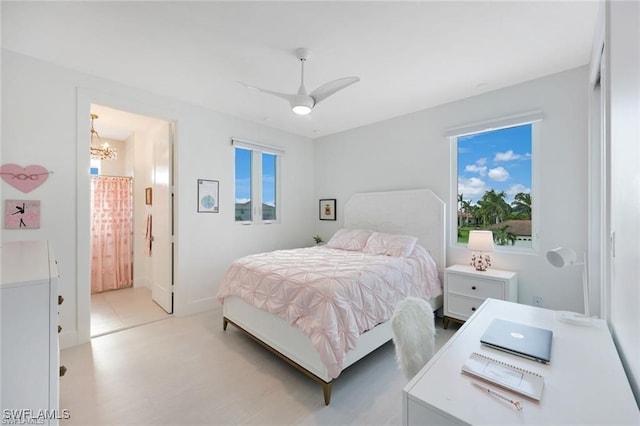 bedroom with connected bathroom and ceiling fan with notable chandelier