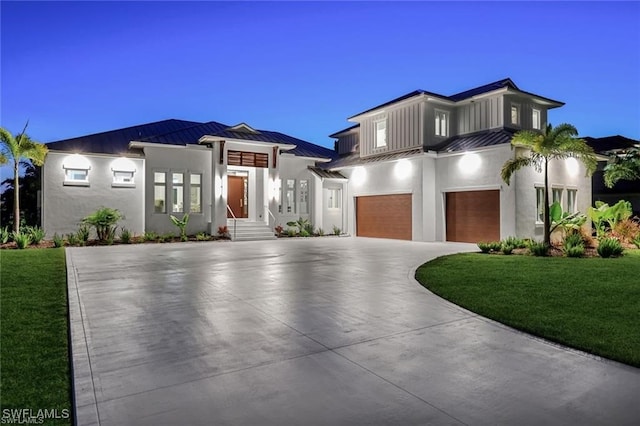 contemporary house with a garage, a standing seam roof, a yard, and driveway