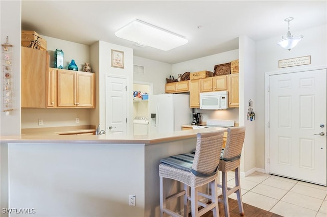 kitchen with white appliances, a breakfast bar, hanging light fixtures, light countertops, and light brown cabinets