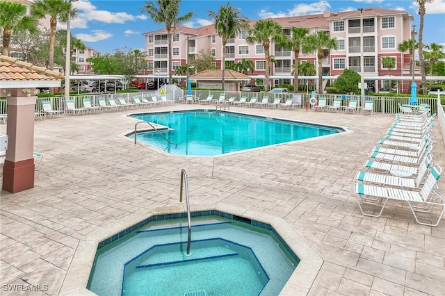 community pool with a community hot tub, fence, and a patio