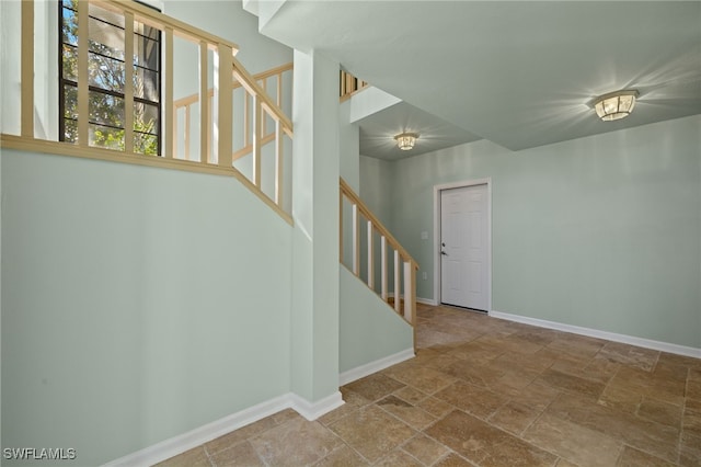 unfurnished room with stairway, stone finish floor, and baseboards