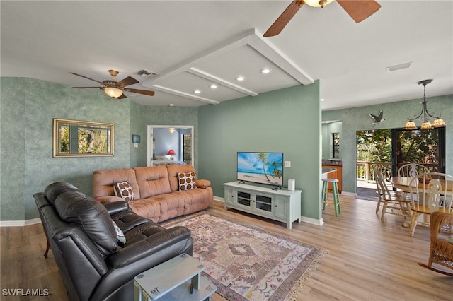 living area featuring an accent wall, visible vents, baseboards, and wood finished floors