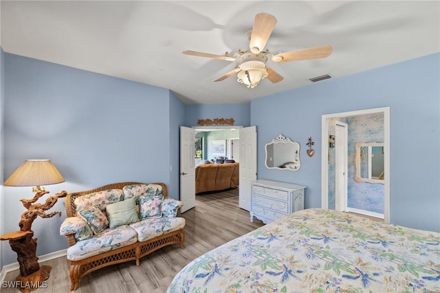 bedroom with a ceiling fan, baseboards, visible vents, and wood finished floors