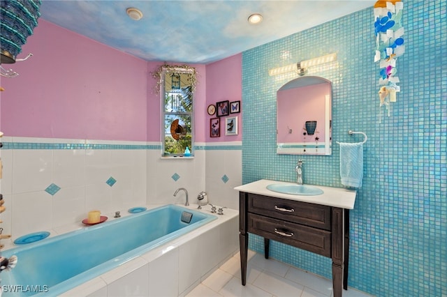 bathroom with a garden tub, vanity, tile walls, and tile patterned floors