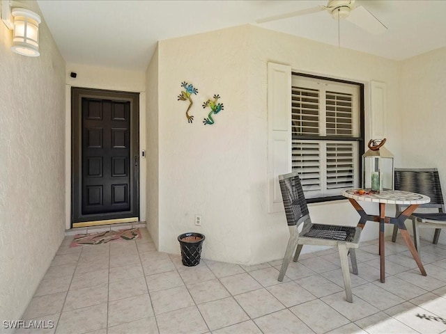 property entrance featuring ceiling fan and stucco siding