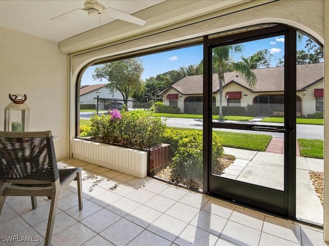 doorway with ceiling fan, a residential view, a textured wall, and light tile patterned floors