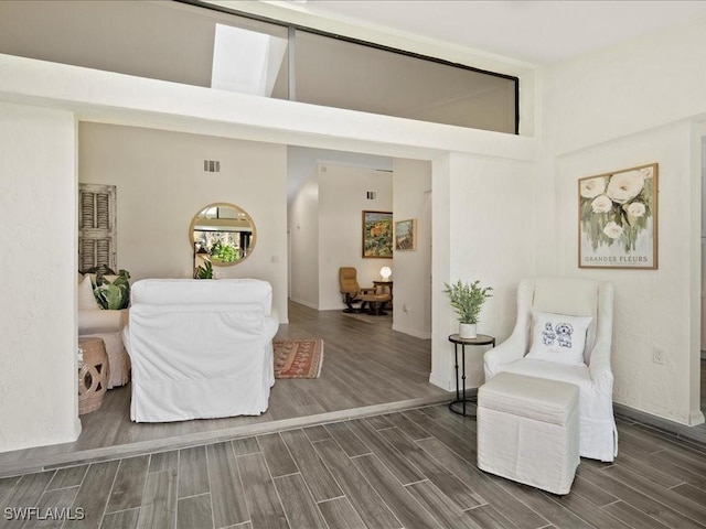 sitting room with wood tiled floor, a high ceiling, and visible vents