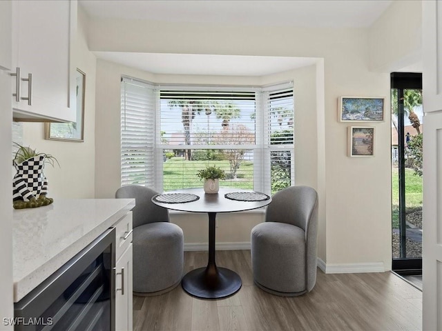 dining area featuring baseboards, wine cooler, a wealth of natural light, and light wood-style floors