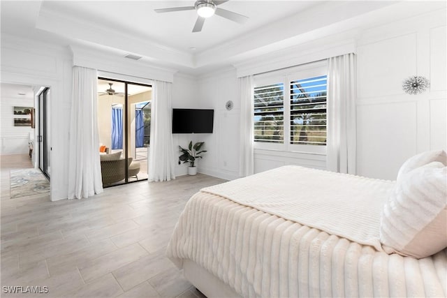 bedroom with access to exterior, a raised ceiling, a decorative wall, and ornamental molding