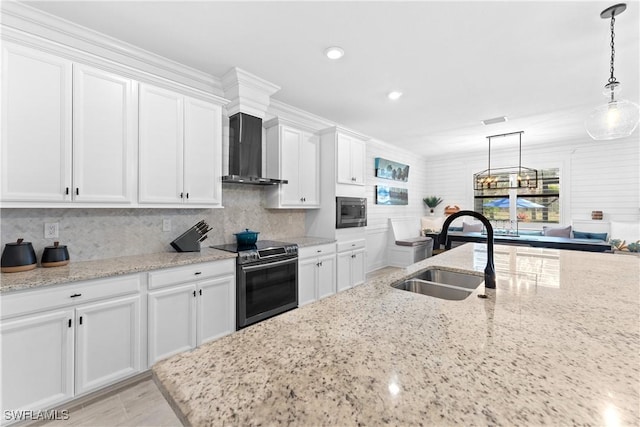 kitchen with appliances with stainless steel finishes, white cabinetry, a sink, and wall chimney range hood