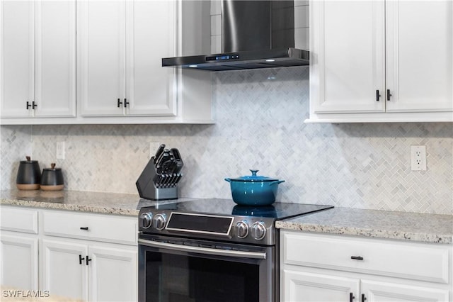 kitchen with decorative backsplash, white cabinetry, stainless steel electric range, and wall chimney exhaust hood