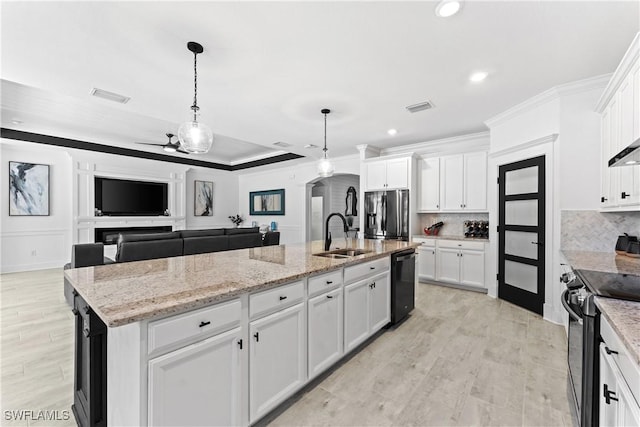 kitchen with stainless steel appliances, white cabinets, a kitchen island with sink, and a sink