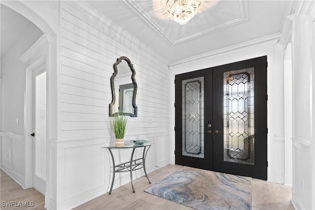 entryway with french doors, a decorative wall, wood tiled floor, and crown molding