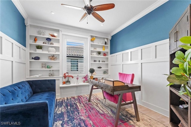 office area featuring built in shelves, crown molding, a decorative wall, and a ceiling fan