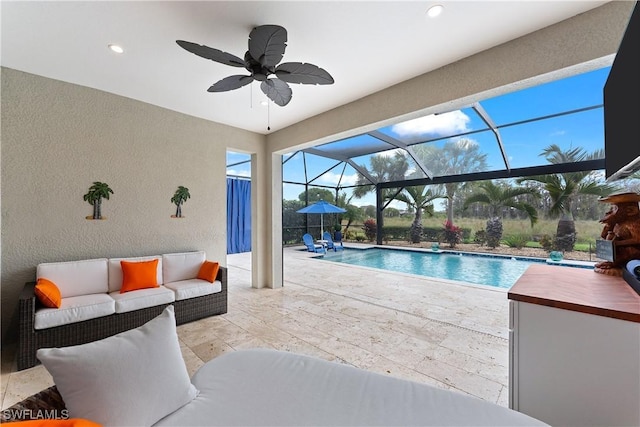 outdoor pool with glass enclosure, an outdoor hangout area, a ceiling fan, and a patio