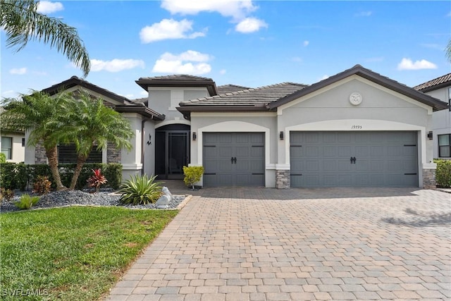 view of front facade featuring decorative driveway, stone siding, an attached garage, and stucco siding