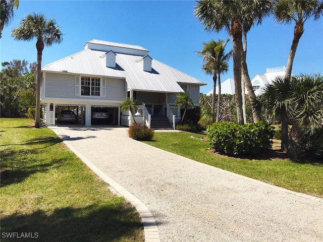 view of front of property featuring driveway, metal roof, a porch, a carport, and a front yard