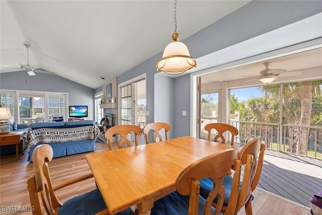 dining space featuring lofted ceiling, light wood-style floors, ceiling fan, and a fireplace