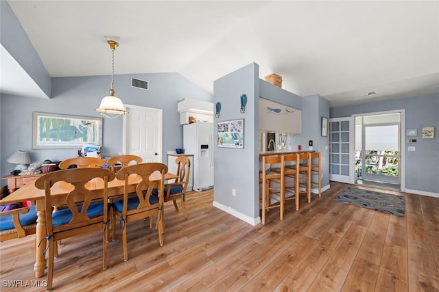 dining room featuring lofted ceiling, light wood finished floors, plenty of natural light, and visible vents