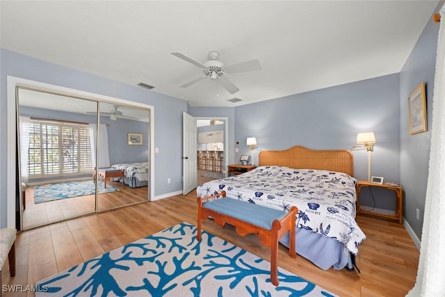 bedroom with ceiling fan, wood finished floors, visible vents, baseboards, and a closet