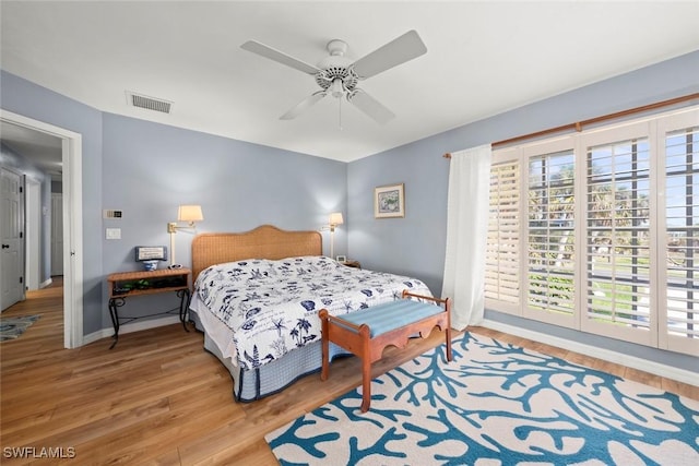 bedroom with baseboards, ceiling fan, visible vents, and wood finished floors