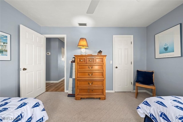 bedroom featuring a ceiling fan, visible vents, light carpet, and baseboards