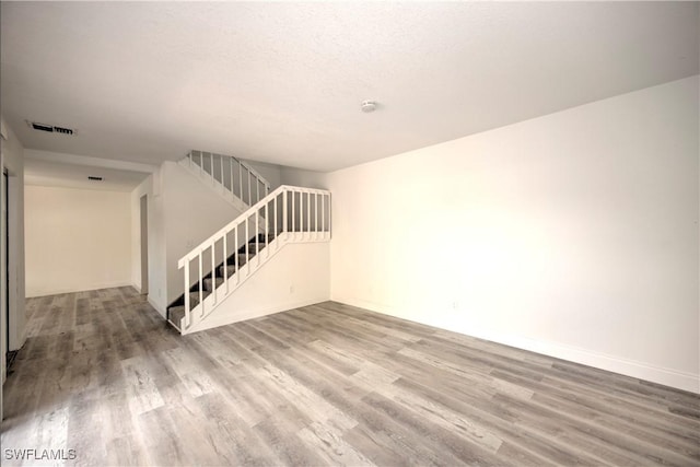 interior space with visible vents, stairway, a textured ceiling, and wood finished floors