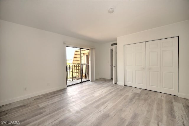 unfurnished bedroom featuring light wood-style flooring, baseboards, access to outside, and a closet