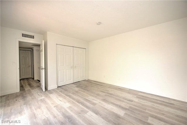 unfurnished bedroom with light wood-style flooring, a closet, visible vents, and baseboards